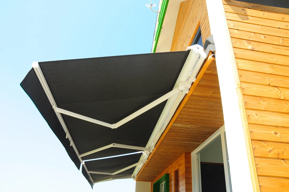 Terrasse extérieure avec store banne déployé sous ciel bleu