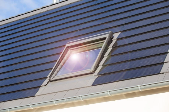 Fenêtre de toit sur une maison individuelle avec des tuiles solaires