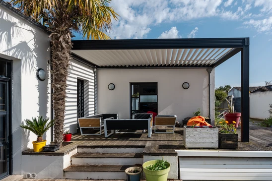 Terrasse extérieure moderne avec pergola bioclimatique à lames orientables, mobilier de jardin contemporain sur plancher bois